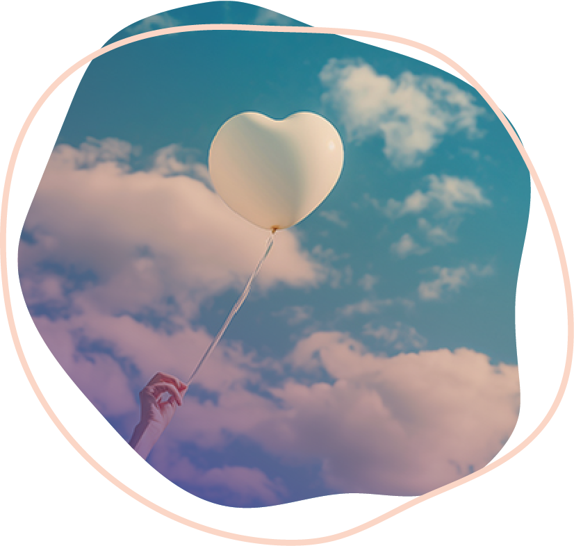 A person holding a heart shaped balloon up to the sky