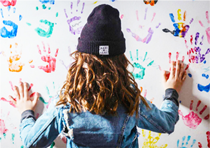 A child touching painted handprints on a wall