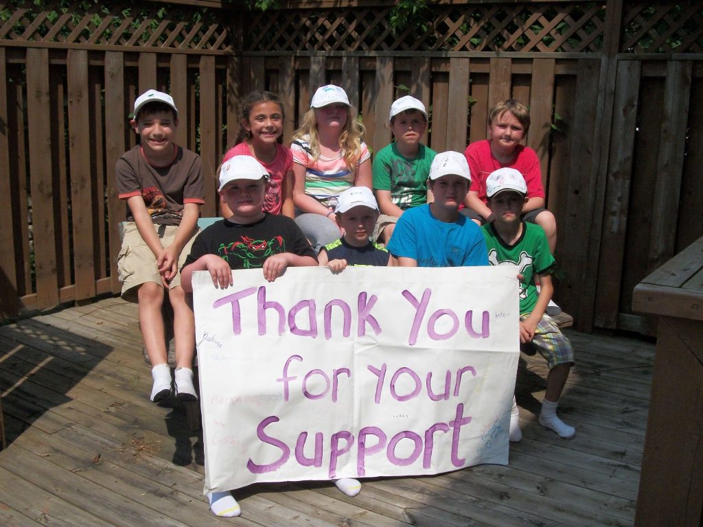 A child group photo with a "Thank you for your support" sign