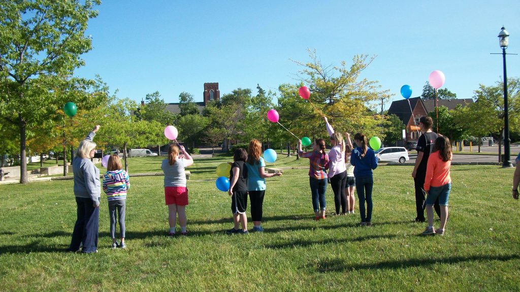 Children partaking in a balloon release activity outside